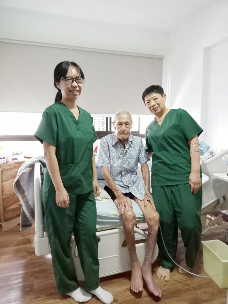 Two Metta Hospice Care staff beside an elderly man